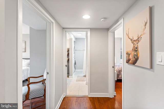 hallway with hardwood / wood-style floors and washer / dryer