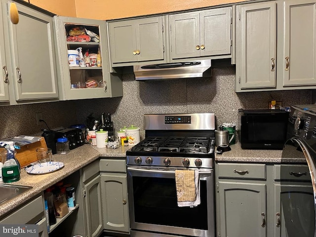 kitchen featuring backsplash, range hood, stainless steel gas stove, and gray cabinetry