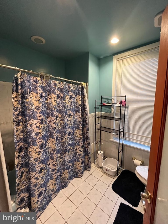 bathroom featuring tile walls, toilet, and tile floors