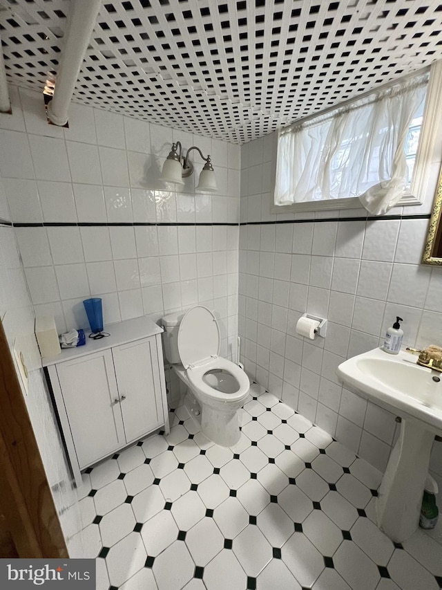 bathroom featuring toilet, tile floors, and tile walls