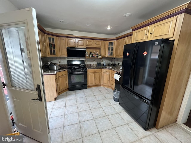 kitchen with dark stone countertops, black appliances, sink, and light tile flooring