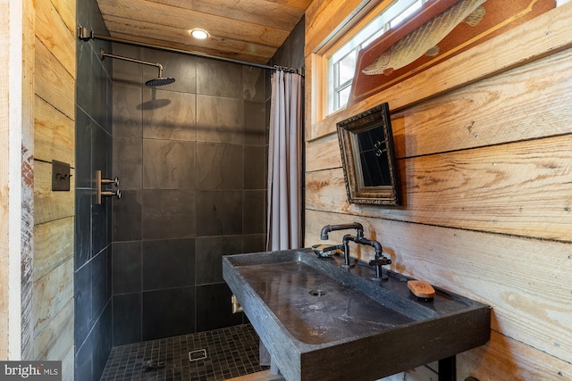 bathroom with sink, walk in shower, wooden walls, and wood ceiling