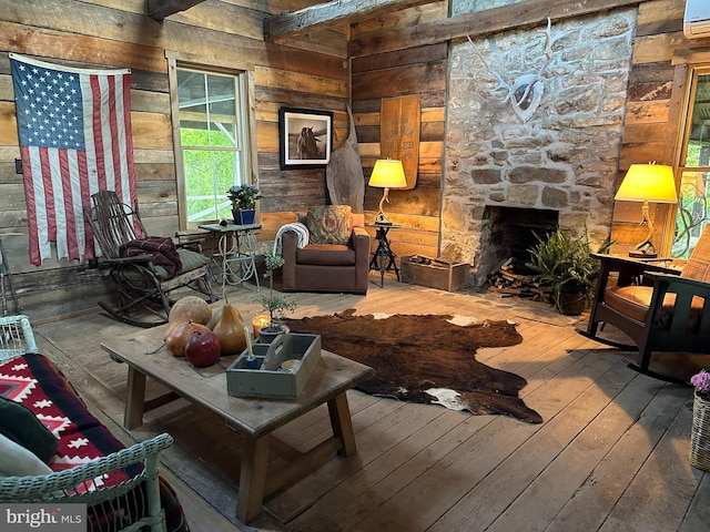 living room with a fireplace, wood walls, a wall unit AC, and hardwood / wood-style floors