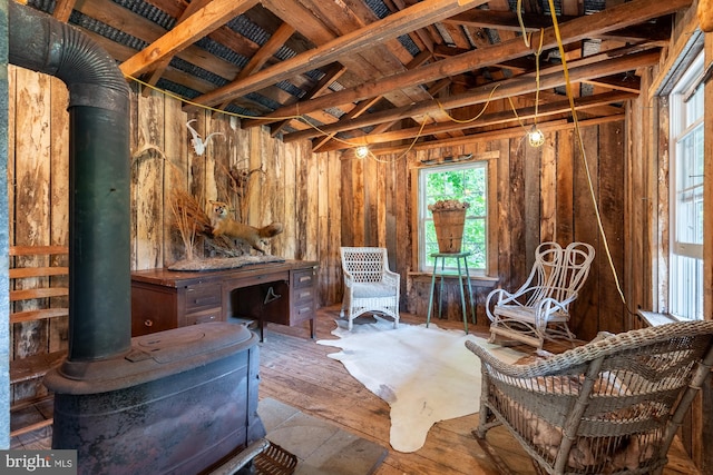 sitting room with wood-type flooring, vaulted ceiling, wooden walls, and a wood stove