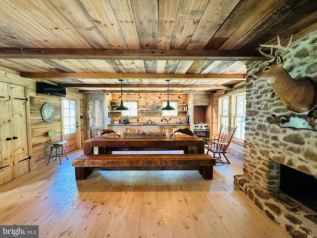 interior space with light hardwood / wood-style flooring, a fireplace, wood walls, beam ceiling, and wood ceiling