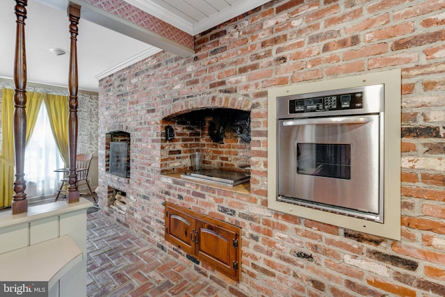 kitchen with brick wall, ornamental molding, and oven