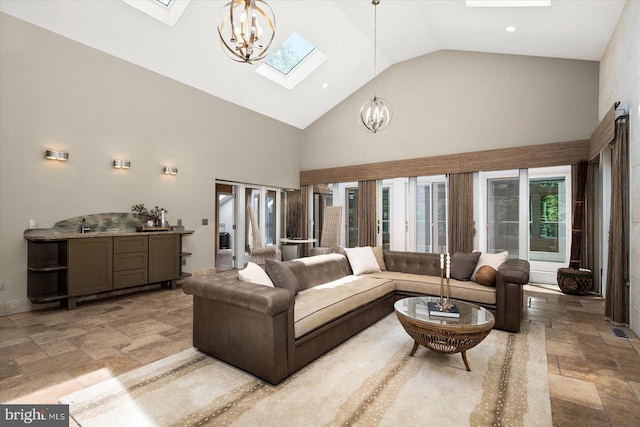 tiled living room with a skylight, a wealth of natural light, high vaulted ceiling, and a chandelier