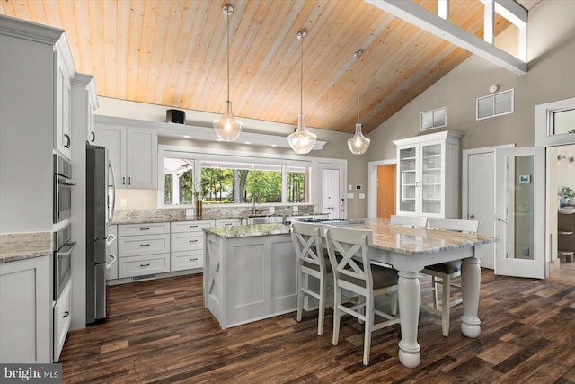 kitchen featuring decorative light fixtures, high vaulted ceiling, light stone countertops, wooden ceiling, and a kitchen island