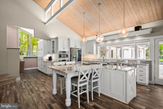 kitchen featuring high vaulted ceiling, appliances with stainless steel finishes, white cabinets, pendant lighting, and a center island