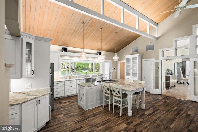 kitchen with white cabinets, wooden ceiling, high vaulted ceiling, and a kitchen island