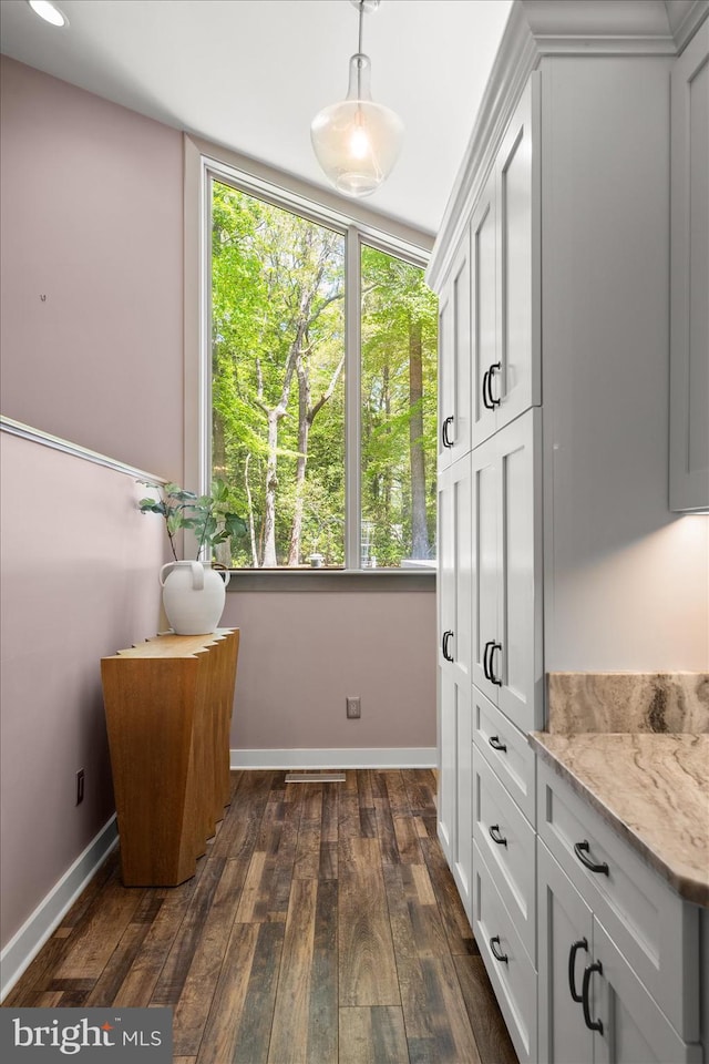 interior space featuring white cabinets, hanging light fixtures, dark wood-type flooring, and light stone countertops