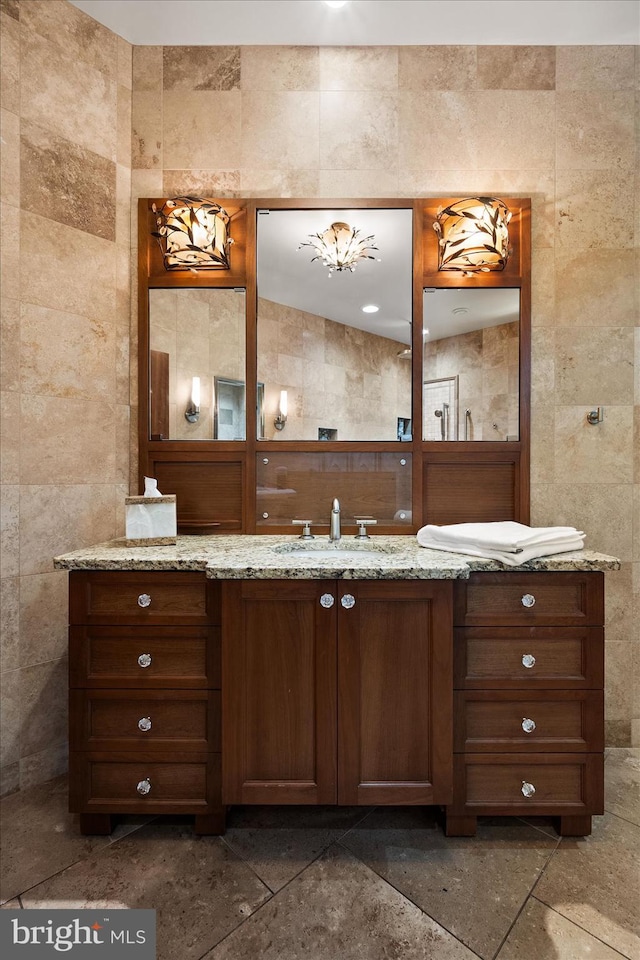 bathroom featuring vanity with extensive cabinet space, tile flooring, and tile walls