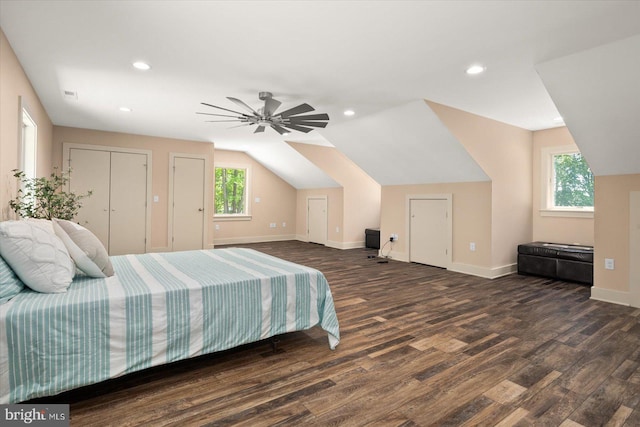 bedroom with dark hardwood / wood-style floors, ceiling fan, vaulted ceiling, and two closets