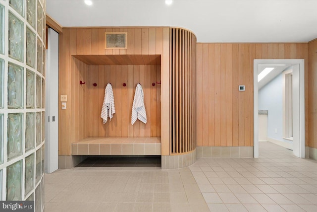 mudroom featuring wood walls and light tile floors