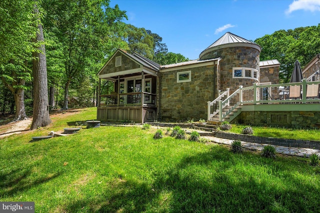 rear view of property with a wooden deck and a lawn