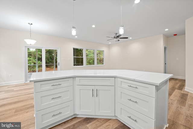 kitchen featuring white cabinets, hanging light fixtures, ceiling fan, light stone countertops, and light wood-type flooring