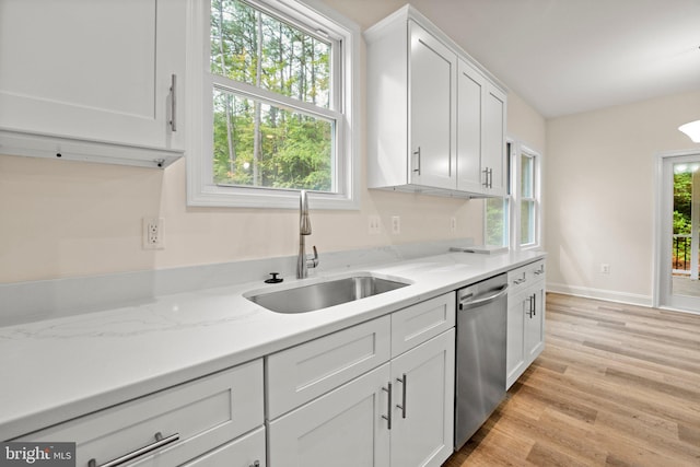 kitchen featuring dishwasher, sink, light stone counters, light hardwood / wood-style flooring, and white cabinets