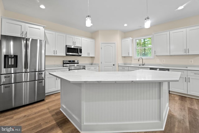 kitchen featuring white cabinets, decorative light fixtures, stainless steel appliances, and a kitchen island