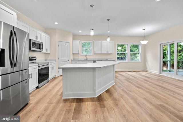 kitchen with pendant lighting, white cabinetry, stainless steel appliances, and a wealth of natural light