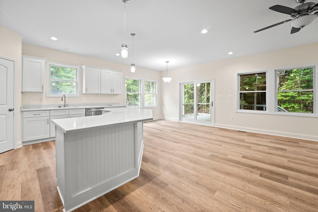 kitchen featuring white cabinetry, light stone countertops, decorative light fixtures, and light wood-type flooring