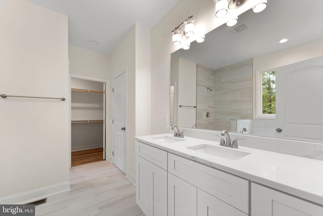 bathroom with tiled shower, hardwood / wood-style floors, and vanity