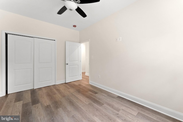 unfurnished bedroom featuring ceiling fan, a closet, and light wood-type flooring