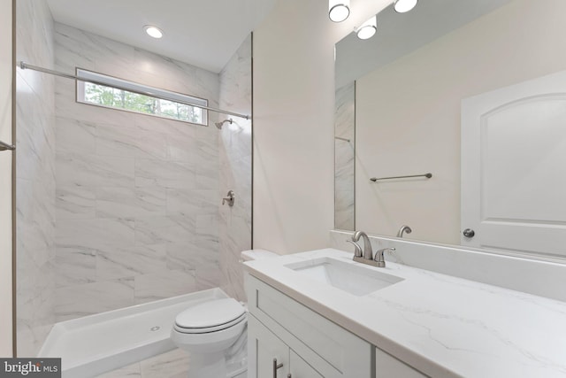 bathroom with a tile shower, vanity, and toilet