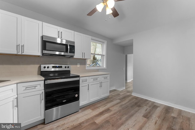 kitchen featuring decorative backsplash, ceiling fan, light wood-type flooring, appliances with stainless steel finishes, and white cabinetry