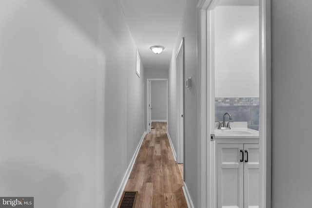 corridor with wood-type flooring and sink