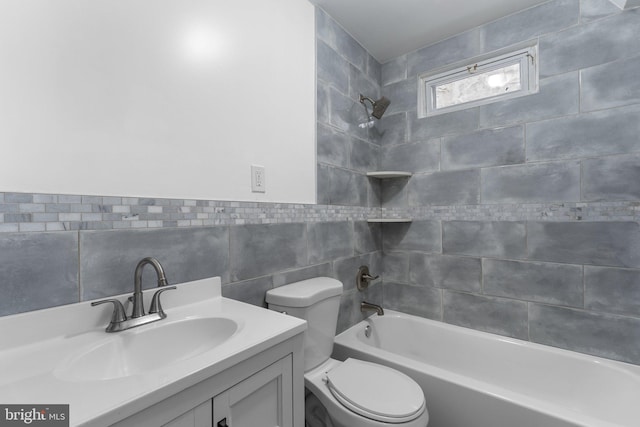 full bathroom with vanity, tiled shower / bath combo, toilet, and tile walls