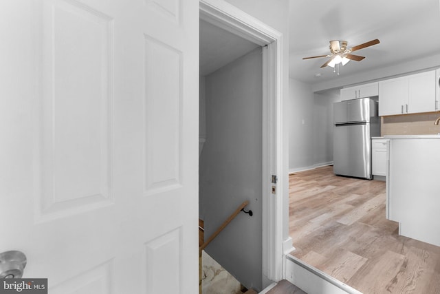 interior space featuring stainless steel fridge, light hardwood / wood-style floors, white cabinetry, and ceiling fan