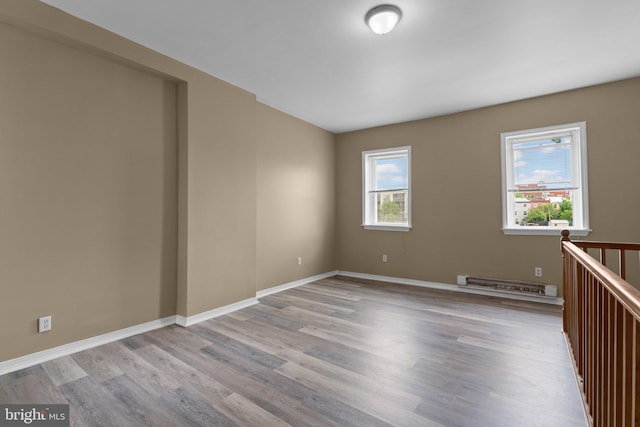 unfurnished room with light wood-type flooring and a baseboard heating unit