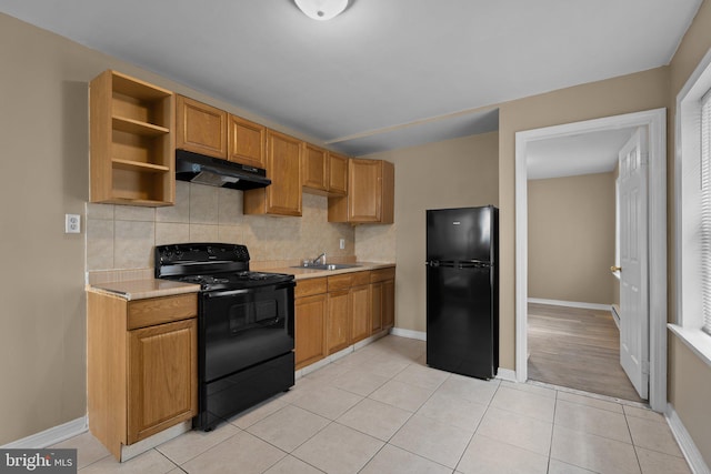 kitchen with decorative backsplash, sink, light hardwood / wood-style floors, and black appliances