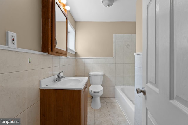 bathroom with a washtub, tile patterned floors, toilet, vanity, and tile walls