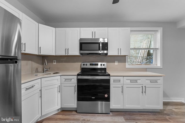 kitchen featuring sink, white cabinets, light wood-type flooring, and appliances with stainless steel finishes