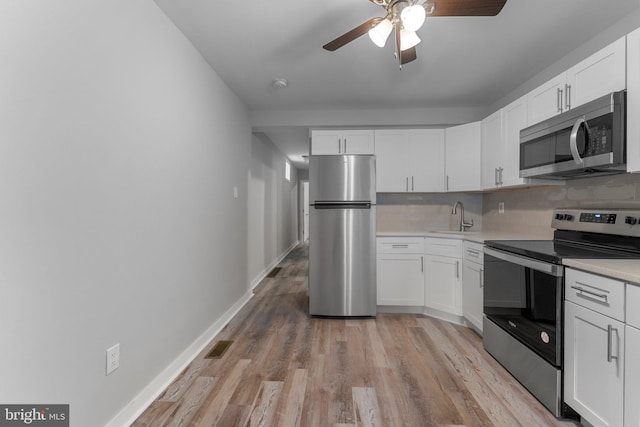 kitchen with backsplash, stainless steel appliances, and white cabinetry