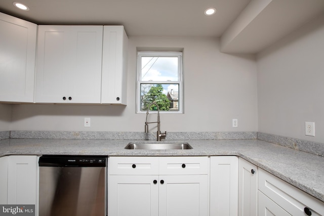 kitchen featuring stainless steel dishwasher, sink, and white cabinetry