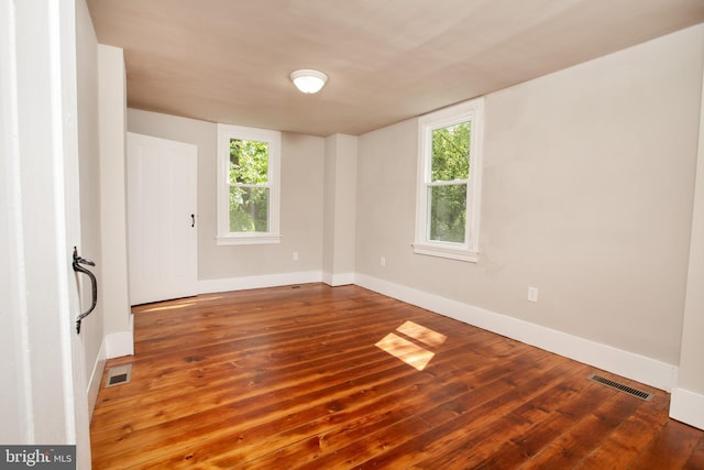 empty room with hardwood / wood-style flooring and plenty of natural light