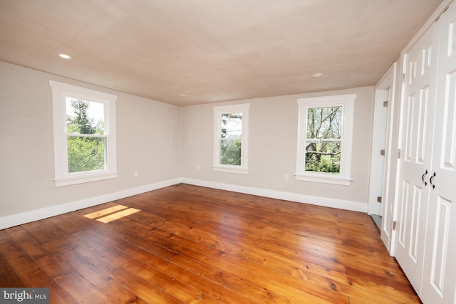 empty room featuring wood-type flooring and a healthy amount of sunlight