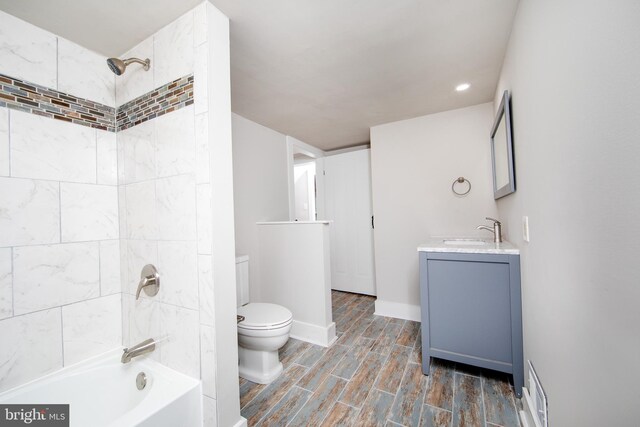 full bathroom featuring tiled shower / bath combo, vanity, and toilet