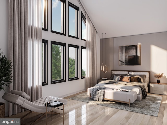 bedroom with light wood-type flooring and high vaulted ceiling