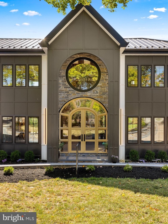 view of exterior entry featuring french doors and a yard