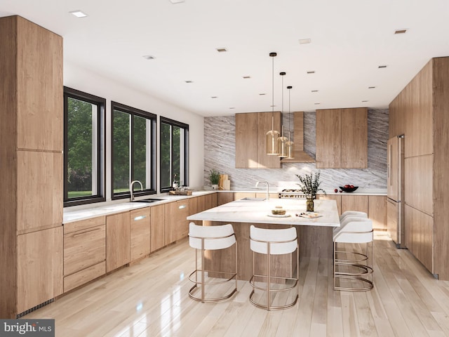 kitchen featuring high end fridge, a center island, sink, and light hardwood / wood-style flooring