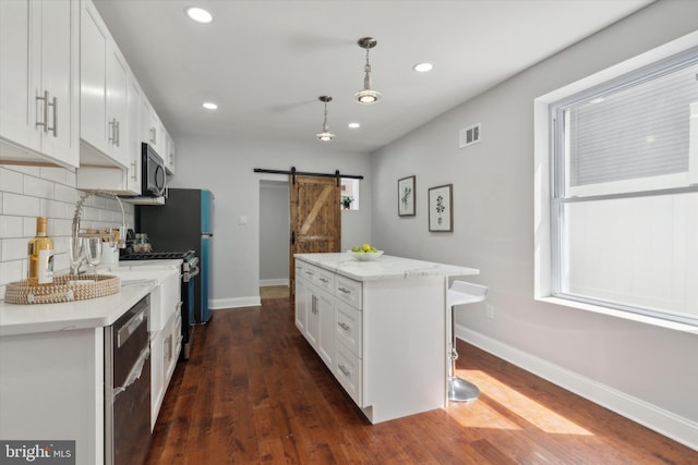 kitchen featuring dark hardwood / wood-style floors, a barn door, white cabinets, and a kitchen island