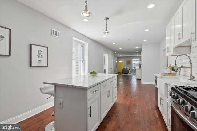 kitchen with a breakfast bar, dark wood-type flooring, white cabinets, and a kitchen island