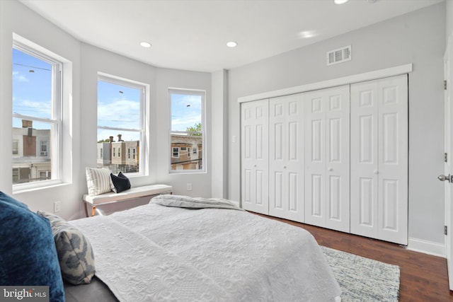 bedroom featuring dark hardwood / wood-style flooring, multiple windows, and a closet