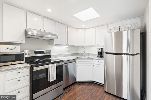 kitchen featuring a skylight, a sink, stainless steel appliances, under cabinet range hood, and white cabinetry