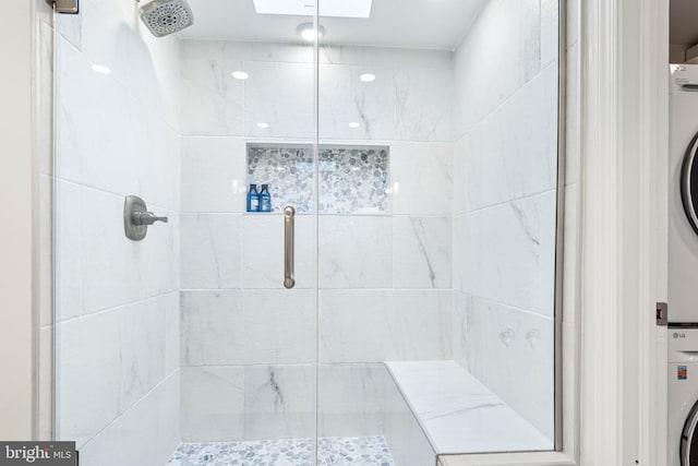 full bath featuring a skylight, a stall shower, and stacked washing maching and dryer