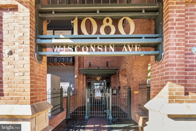 entrance to property with brick siding and a gate