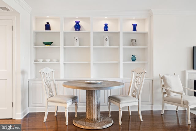 dining space with dark wood finished floors, crown molding, built in features, and visible vents